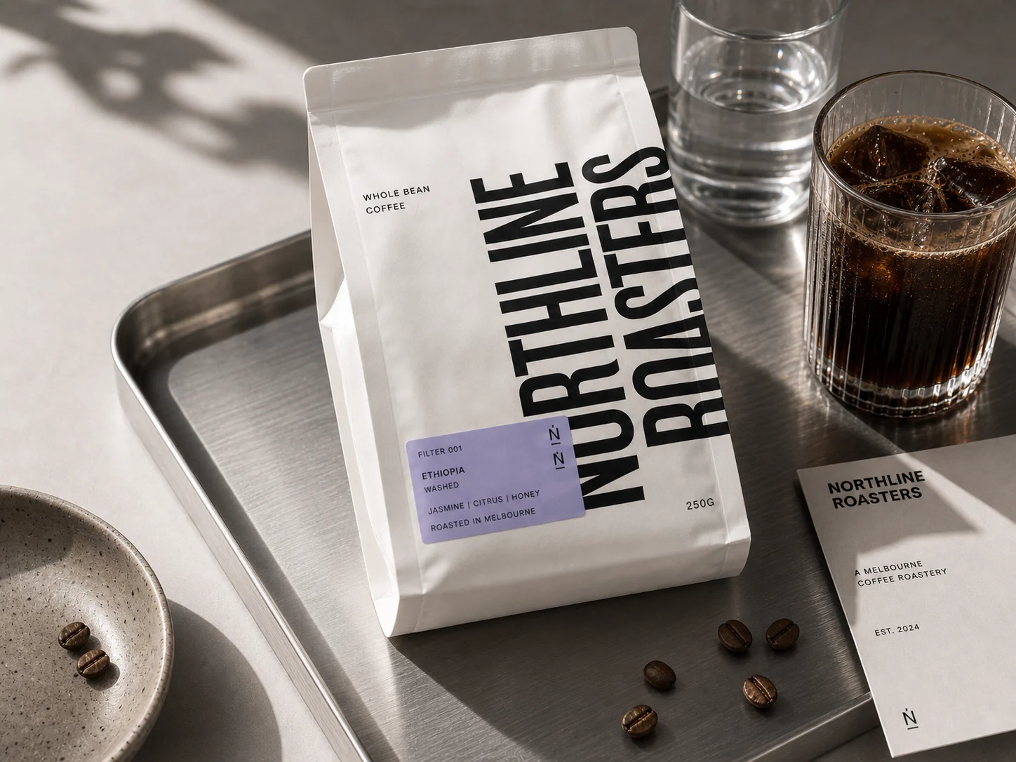 NORTHLINE ROASTERS white coffee bag on a stainless tray beside iced coffee and brand card